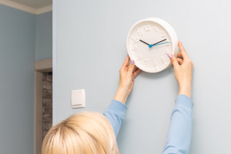 woman hangs a clock on the wall of the room. man hangs a clock on the wallの写真素材