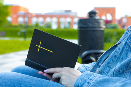 woman reading the bible sitting on a bench. woman reading the bible on the street