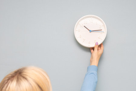woman hangs a clock on the wall of the room. man hangs a clock on the wall. . high quality photoの写真素材
