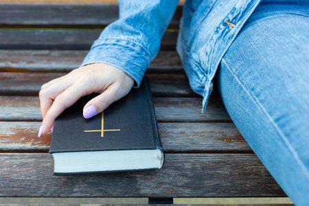 woman holding her hand on the bible lying on the bench. woman holding paper bible