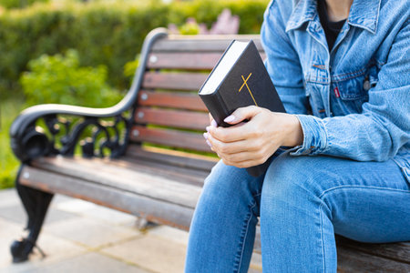 woman reading the bible sitting on a bench. woman reading the bible on the street. woman ask god for...