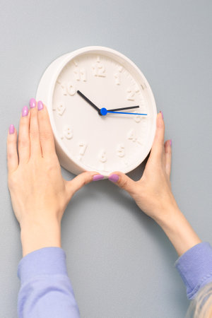 woman hangs a clock on the wall of the room. woman hangs a clock on the wall.の写真素材