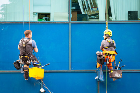 Moscow, Russia - June 02, 2023: high-altitude climber washes the facade of the building. washing the front of the house. industrial climber communicates while workingのeditorial素材
