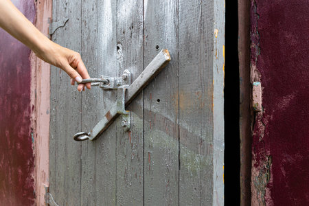 female hand opens the old door leading to the basement. door to old cellar. the hand opens the shadow door behind the ringの写真素材