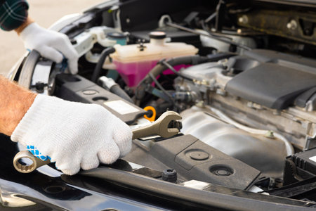 the driver inspects the engine compartment of the car. man with a wrench near the car. car repair...