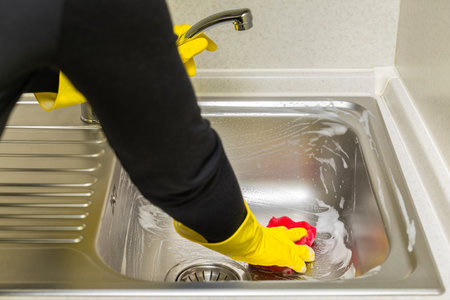 woman in rubber gloves washes the sink in the kitchen. hand in a glove washes the sink in the kitchenの写真素材