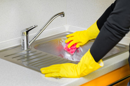 Hand of woman cleaning the kitchen counter and sink at home. woman washing sink in kitchen....