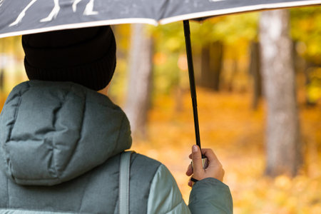 a woman with an umbrella in her hand walks through the autumn park. walk in the autumn park.の写真素材