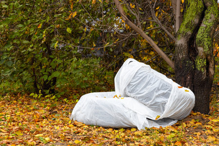 a car tire in a white cover lies in the yard. car tire storageの写真素材