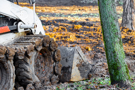 tractor tracks in the mud during work. tractor with bucket during operation. tractor clears the...