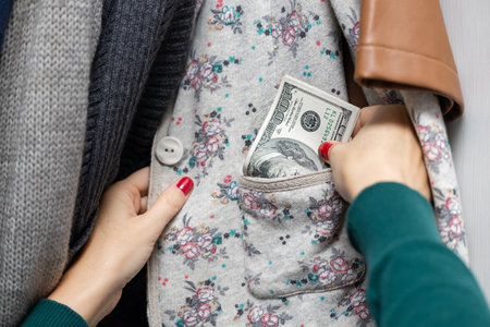 woman hides money in clothes hanging on a hanger in the closet. woman making a stash of dollars....