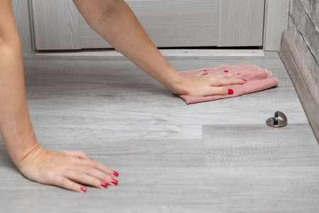 woman with manicure washes the floor with a rag. wet floor cleaning close-upの写真素材