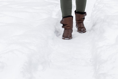 woman in solid shoes walks along a snowy path. man walking along a winter path. after snowfall