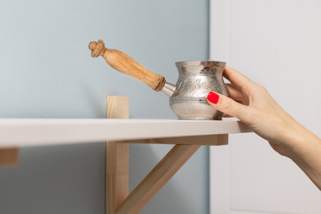 a woman takes a coffee pot from a shelf. old coffee pot. making natural coffeeの写真素材