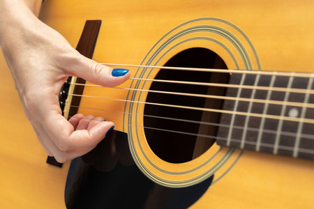 hand runs fingers along the strings of an acoustic guitar. girl playing acoustic guitar, shot...