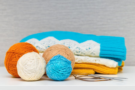 warm knitted clothes lie in a pile. knitted sweater with a ball of wool threads. knitting clothes...