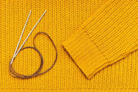 knitting needles and wool threads on a knitted background. knitting a sweater from wool threads.