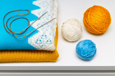 wool knitting needles lie on a knitted sweater. knitted sweater with a ball of wool threads....