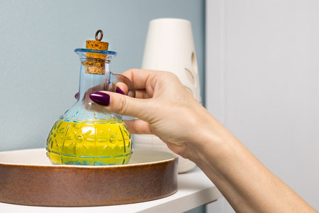 housewife takes a glass bottle of olive oil from a shelf. glass bottle with cooking oil. olive oil bottle man holding a bottle of oil.の写真素材
