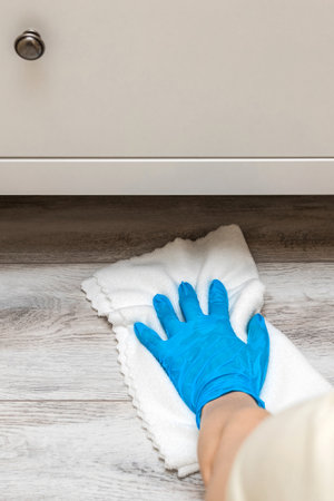 housewife wearing gloves washes the floor under the closet. wet cleaning of the floor in the room....