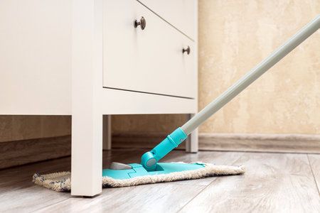 housewife mopping the floor under the closet. wet cleaning of the floor in the room. cleaning dust...