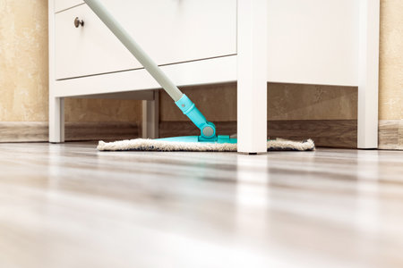 housewife mopping the floor under the closet. wet cleaning of the floor in the room. cleaning dust under cabinets.の写真素材