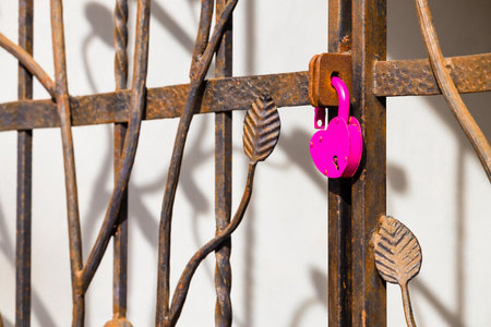 a heart-shaped padlock hanging on a metal gate. open padlock. heart on lock. love relationship