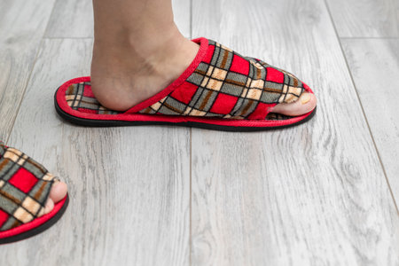 foot shod in an old leaky slipper. old slipper. holey sneaker the toe sticks out of the shoe in the slipperの写真素材