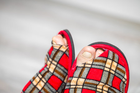 foot shod in an old leaky slipper. old slipper. holey sneaker man in old slippersの写真素材
