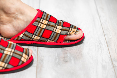 man in old slippers. old slipper. holey sneaker the toe sticks out of the shoe in the slipper.