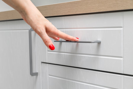 housewife opens a kitchen cabinet drawer with her hand. woman's hand opens the kitchen cabinet
