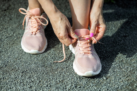 woman typing her sneakers while getting ready for a run. Tying laces on running shoes. preparing for...