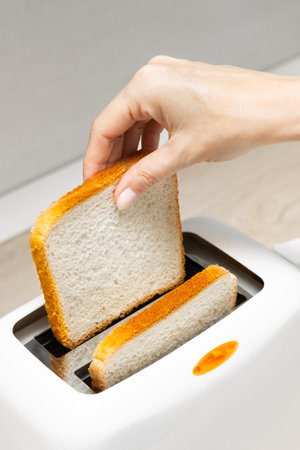 woman's hand putting bread into the toaster. housewife frying bread in a toaster, in the kitchen....
