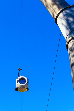 a cable car with round passenger cabins. cable car against blue sky. aerial tram station. the aerial tram arrives at the station. vertical photoの写真素材