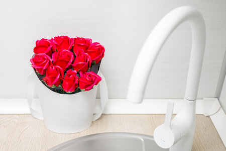 a bouquet of red roses made of soap stands in the kitchen near the sink. soap flowers near the sink. red soap roses. hand washing soap near the kitchen sinkの写真素材