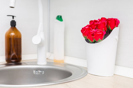 a bouquet of red roses made of soap stands in the kitchen near the sink. soap flowers near the sink. red soap roses. hand washing soap near the kitchen sink.の写真素材