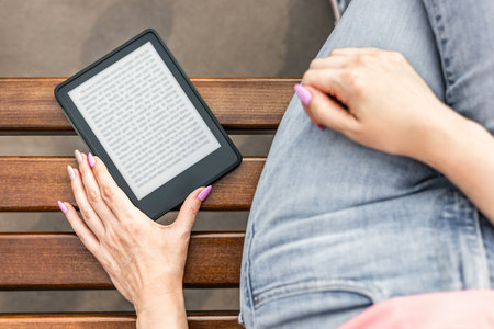 woman reading e-book sitting on bench, close-up. man reading an e-book. ebook mockup. High quality...