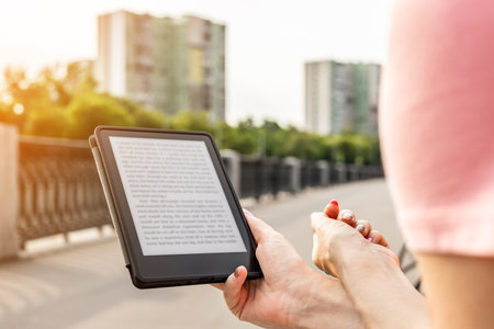 woman reading e-book sitting on bench in city park. man reading an e-book. ebook mockup.の写真素材
