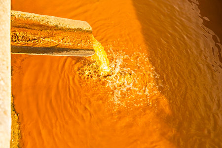 dirty orange water flows down the pipe. Dirty water discharge. water pollution. environmental pollution. drain pipe dirty water ecological disasterの写真素材