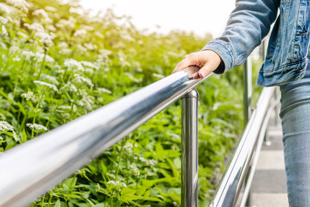 woman walking down stairs in park holding onto handrail. female hand holding metal handrail of staircase. stairs in the park.の写真素材