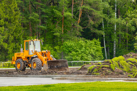 yellow tractor with bucket doing landscaping work. Front loader during operation. landscaping work...