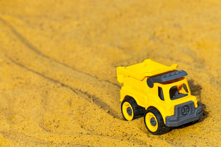 toy yellow car in sandbox, close up. children's toy in the sandbox. car in the sandbox. car wheel tracks on sand. place for descriptionの写真素材