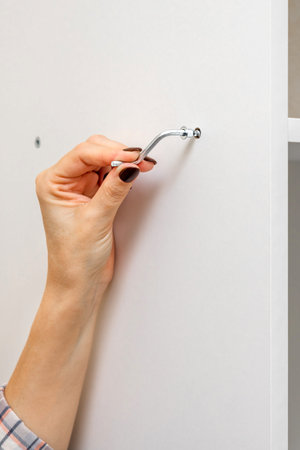 A woman assembles a white shelving unit using an L-shaped wrench. A woman's hand tightens a Euro...