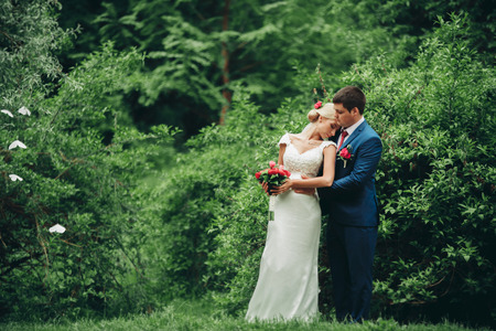 beautiful wedding couple in park. kiss and hug each other.の写真素材