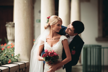 Beautiful couple, bride and groom posing on old balcony with column.の写真素材