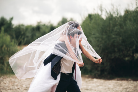 Elegant gentle stylishElegant gentle stylish groom and bride near river with stones. Wedding couple in love.の写真素材