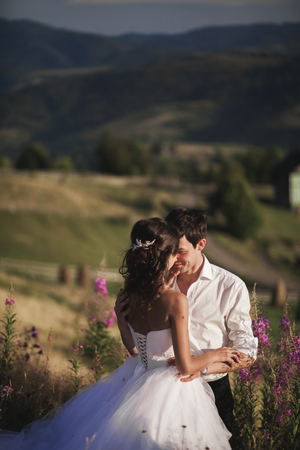 Romantic fairytale couple newlyweds kissing and embracing on a background of mountains.の写真素材