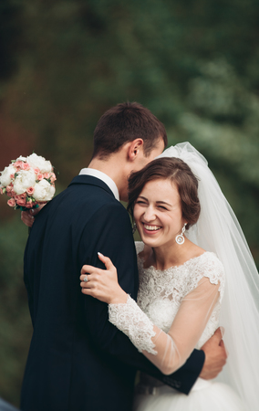Handsome romantic groom and beautiful bride posing near river in scenic mountains.の写真素材