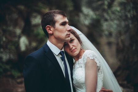 Beautiful wedding couple stay on stone of the river in scenic mountains.の写真素材