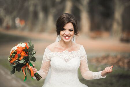Beautiful bride in the park on her wedding day with bouquet.の写真素材